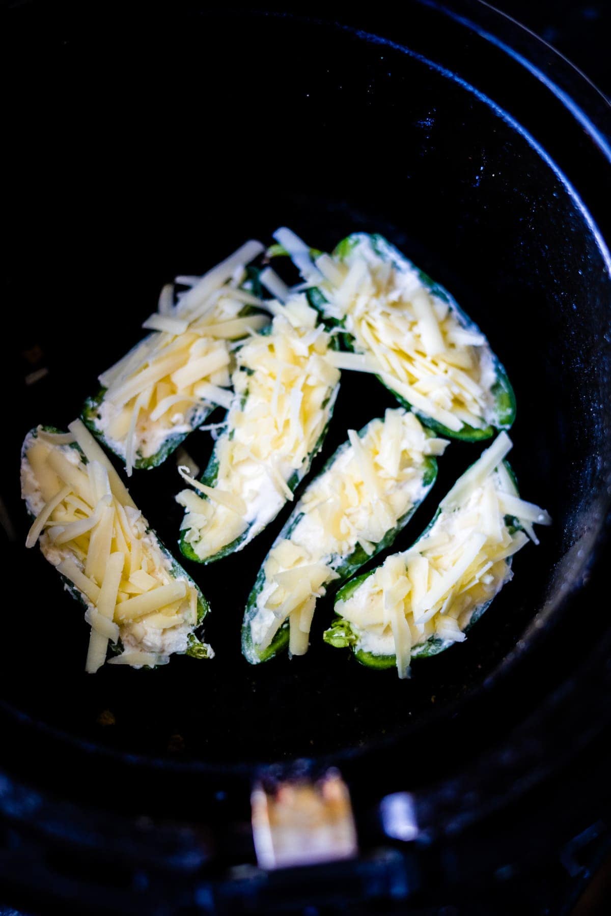 Stuffed jalapeños brimming with cream cheese and shredded cheese are perfectly nestled within a slow cooker.