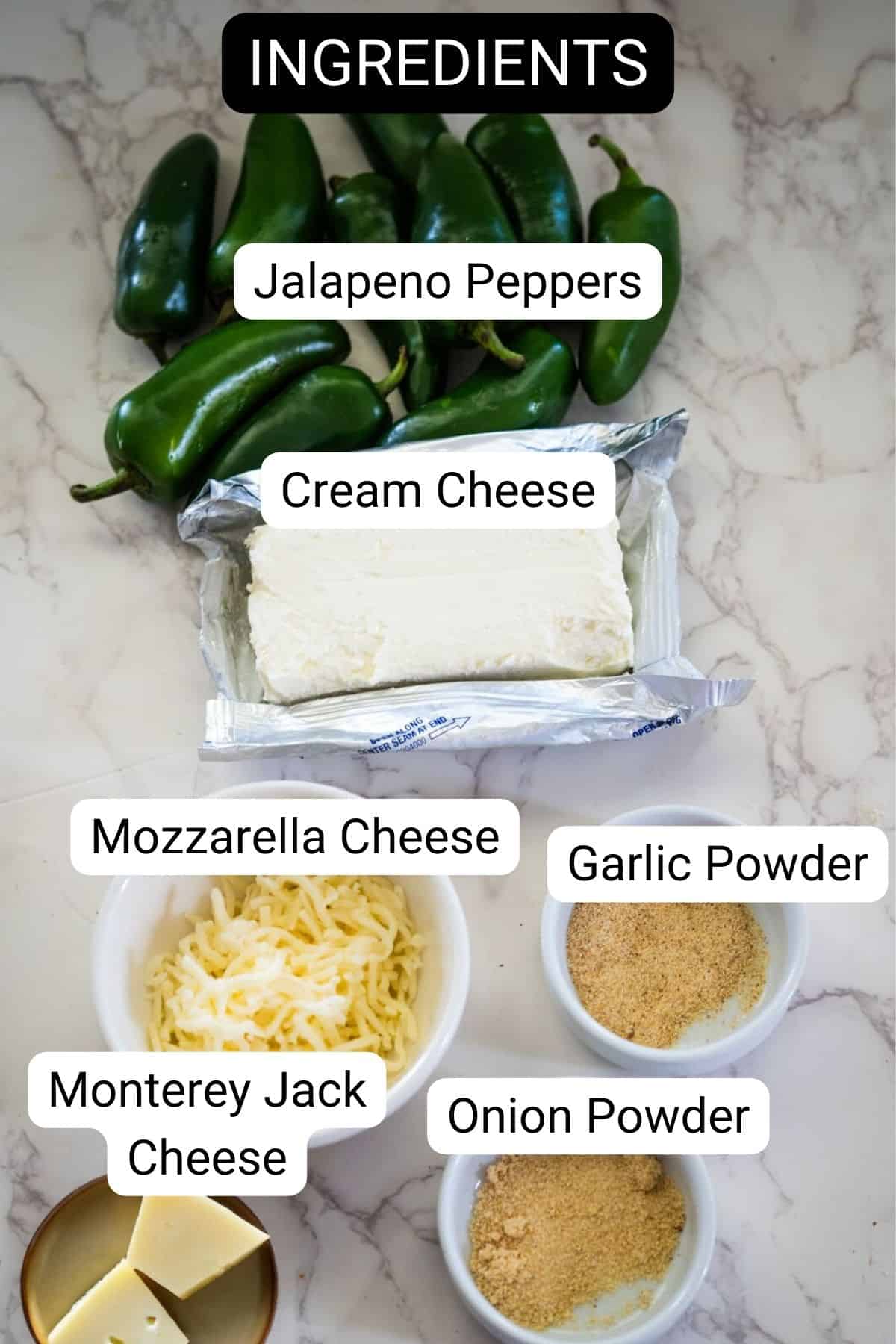 Stuffed jalapeno ingredients on a marble surface: jalapeno peppers, block of cream cheese, shredded mozzarella and Monterey Jack cheese, garlic powder, and onion powder in small bowls.