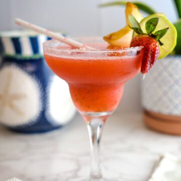 a glass of strawberry daiquiri with fruit garnish