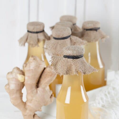 Ginger juice in bottles on a white table.