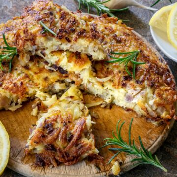 An artichoke frittata garnished with lemon slices and fresh rosemary.