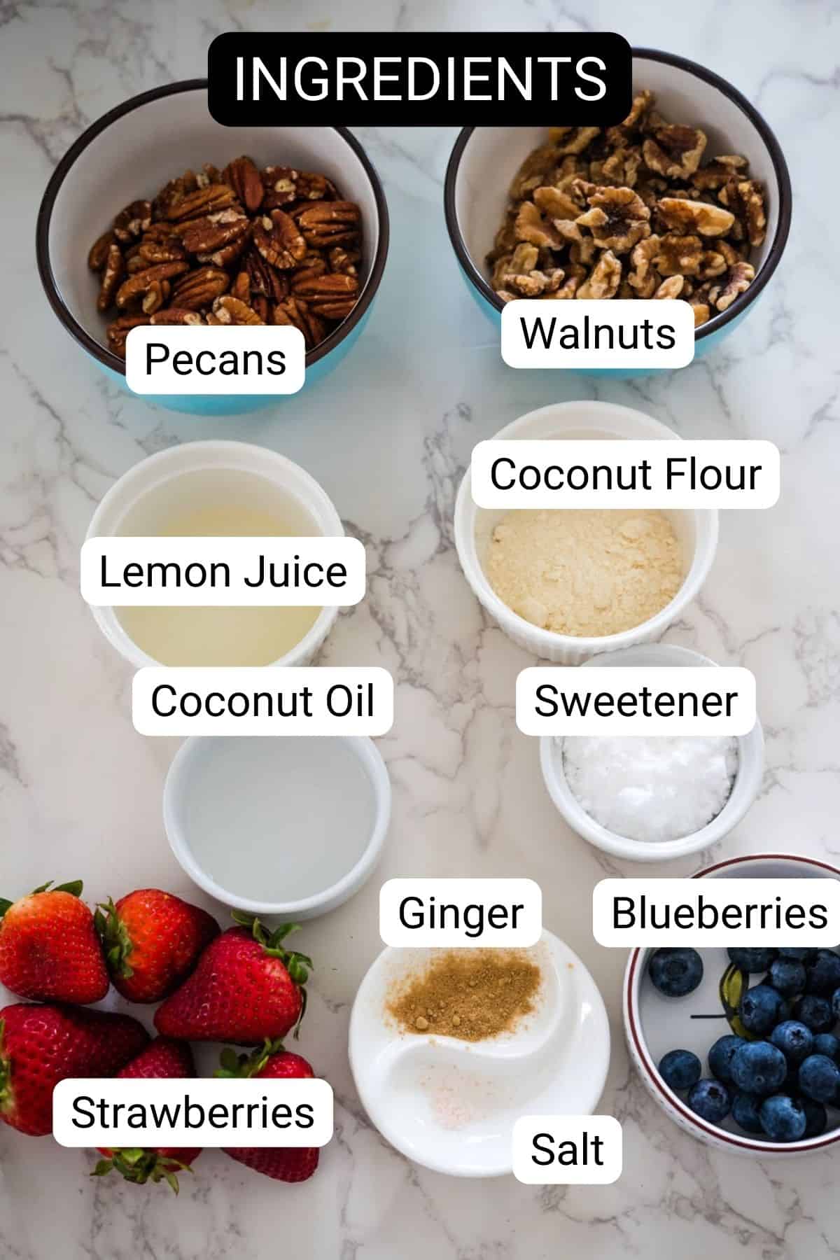 A labeled image of ingredients on a marble surface: pecans, walnuts, coconut flour, lemon juice, coconut oil, sweetener, ginger, blueberries, strawberries, and salt for making keto berry tarts.