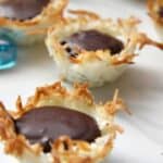 Coconut chocolate macaroon cups arranged on a pristine white surface.