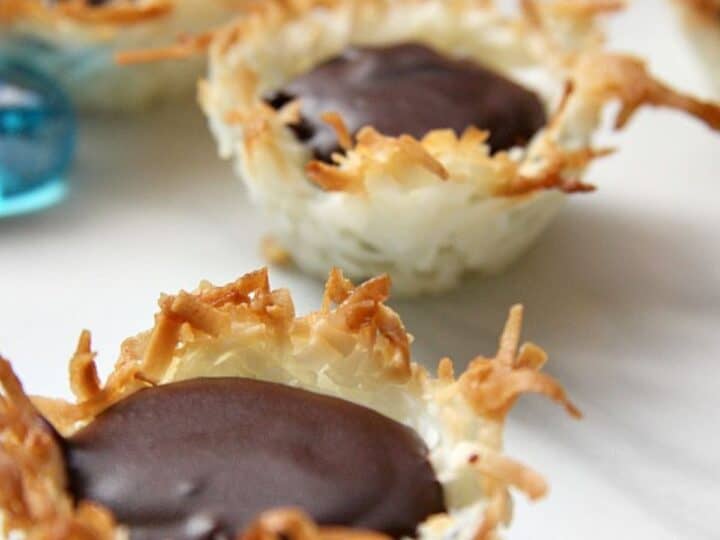 Coconut chocolate macaroon cups arranged on a pristine white surface.