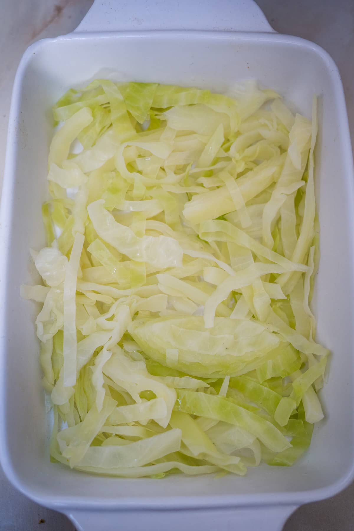 Shredded cabbage in a white baking dish.