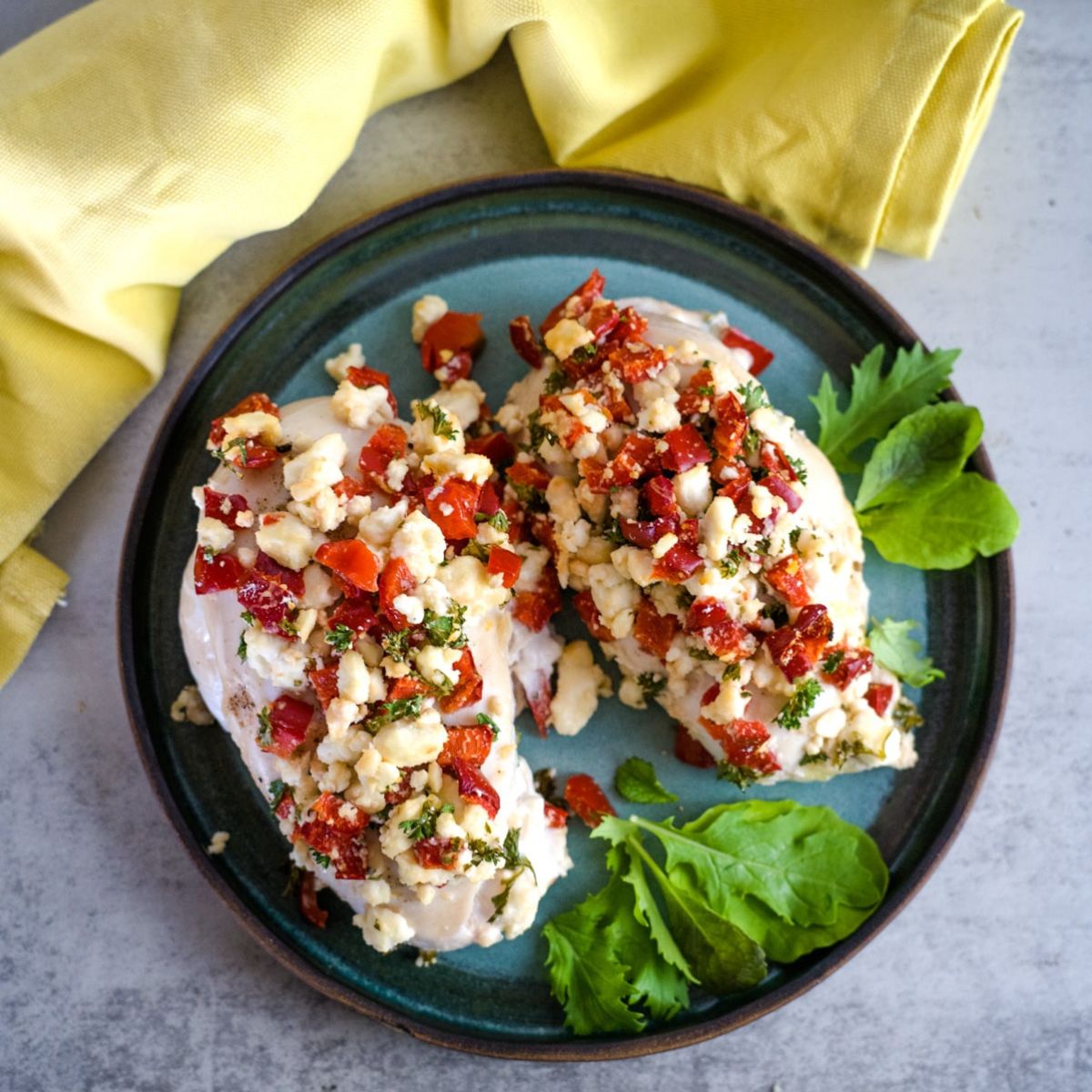 chicken breasts with chopped red pepper and feta cheese on a plate