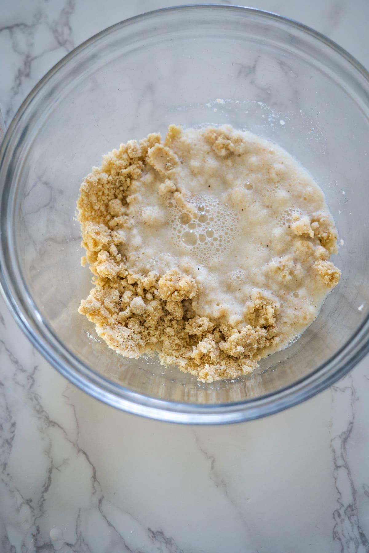A glass bowl filled with a mixture of ingredients for coconut flour flatbread.