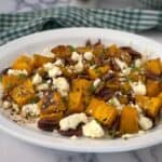 Roasted pumpkin with feta and pecans on a white plate.