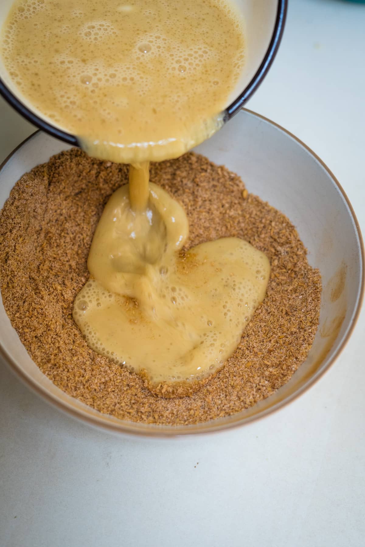 A bowl of flaxseed pancakes being poured into a bowl.