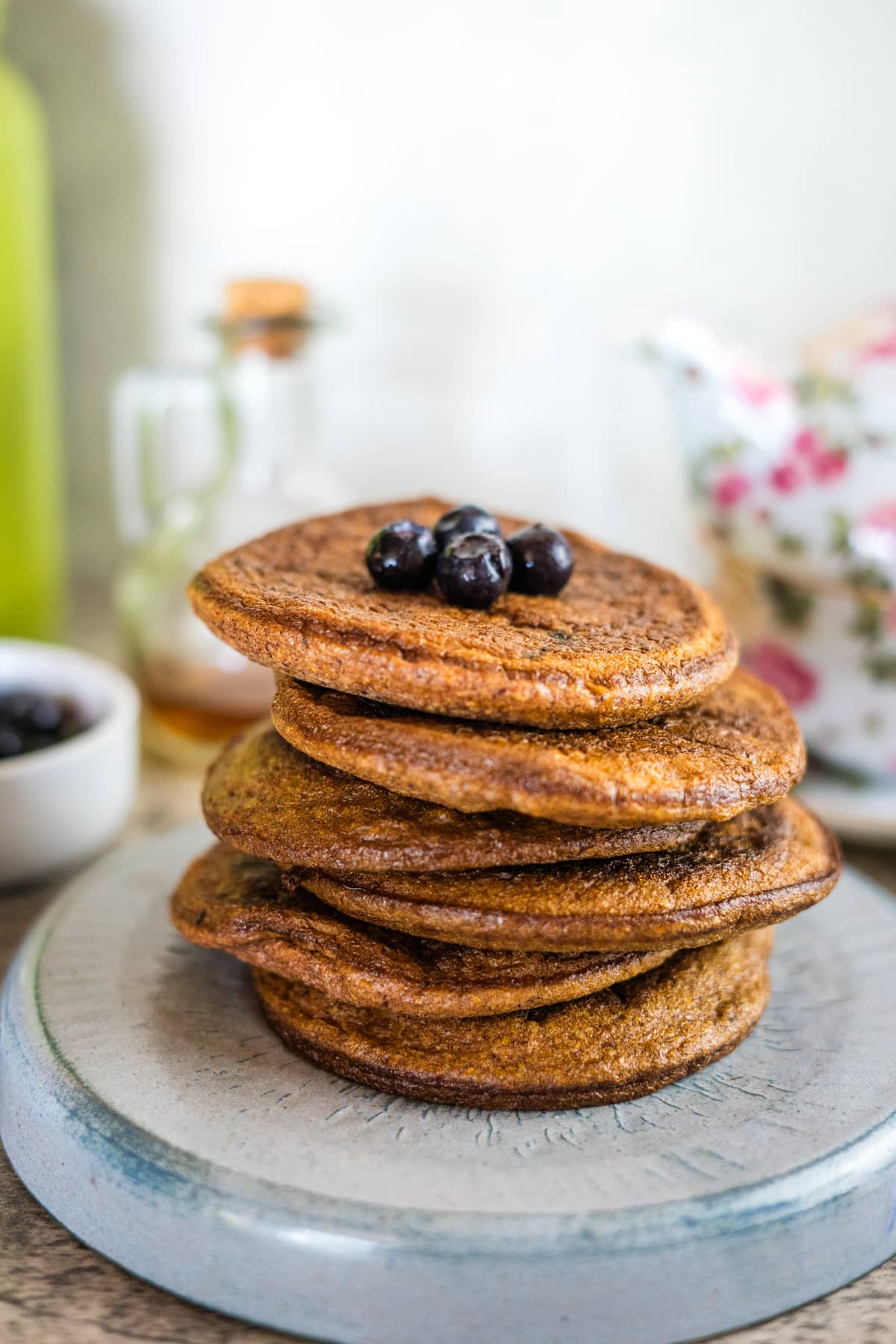 A stack of flaxseed pancakes with blueberries on a plate.