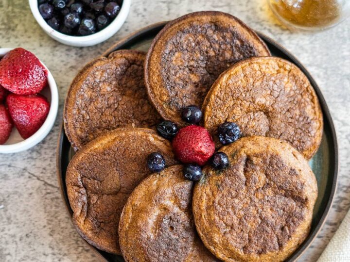 Flaxseed pancakes with berries and syrup on a plate.