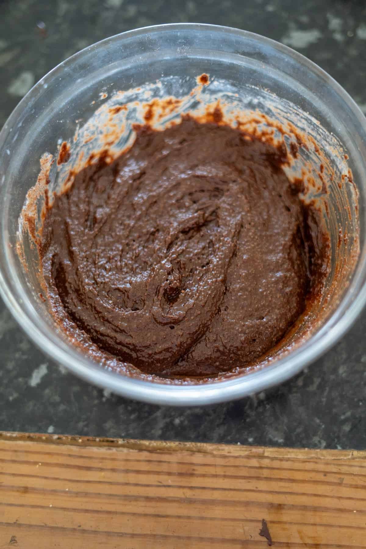 Bowl of thick chocolate batter on a dark countertop.