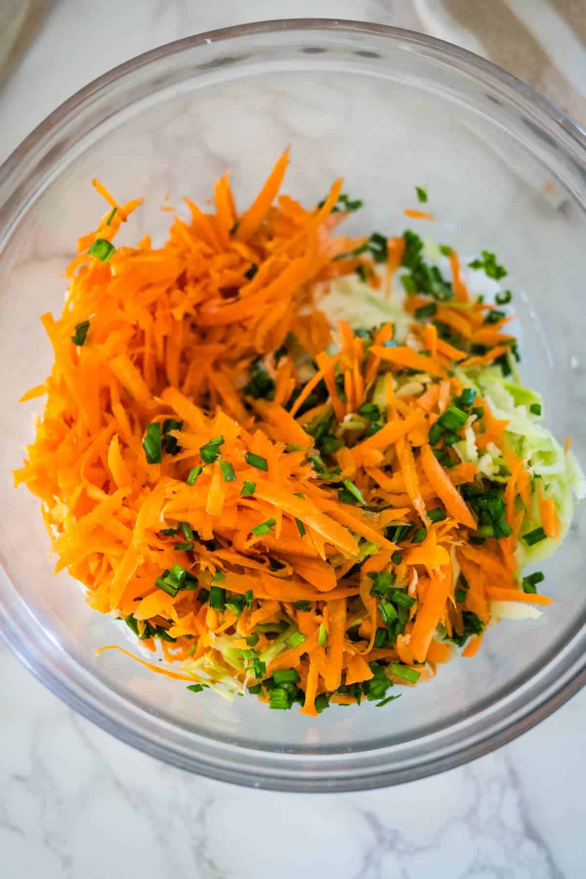 Shredded broccoli coleslaw and parsley in a bowl.