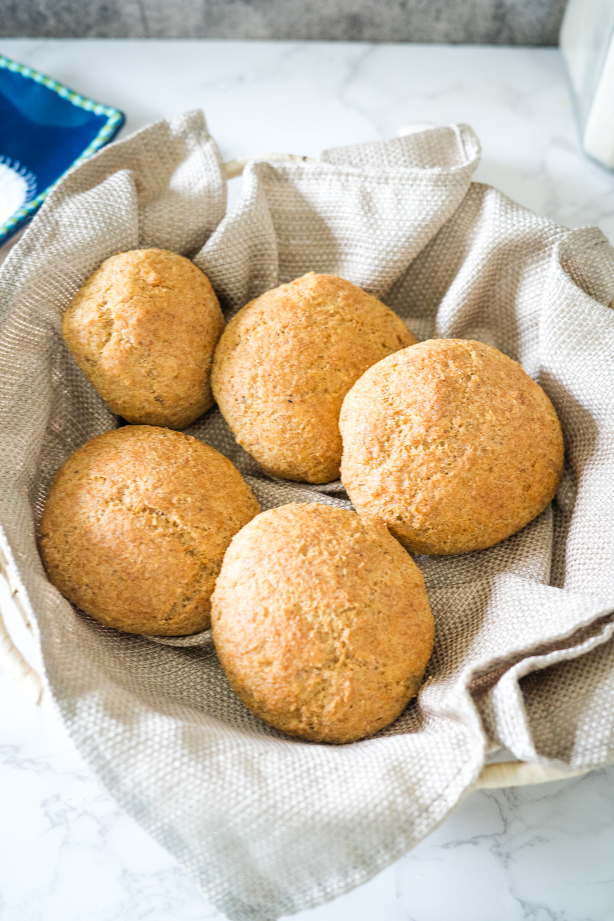 A bowl of flaxseed bread buns sitting on a table.