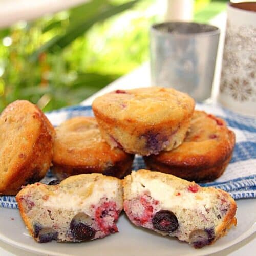 A plate of muffins with cream cheese and blueberries.