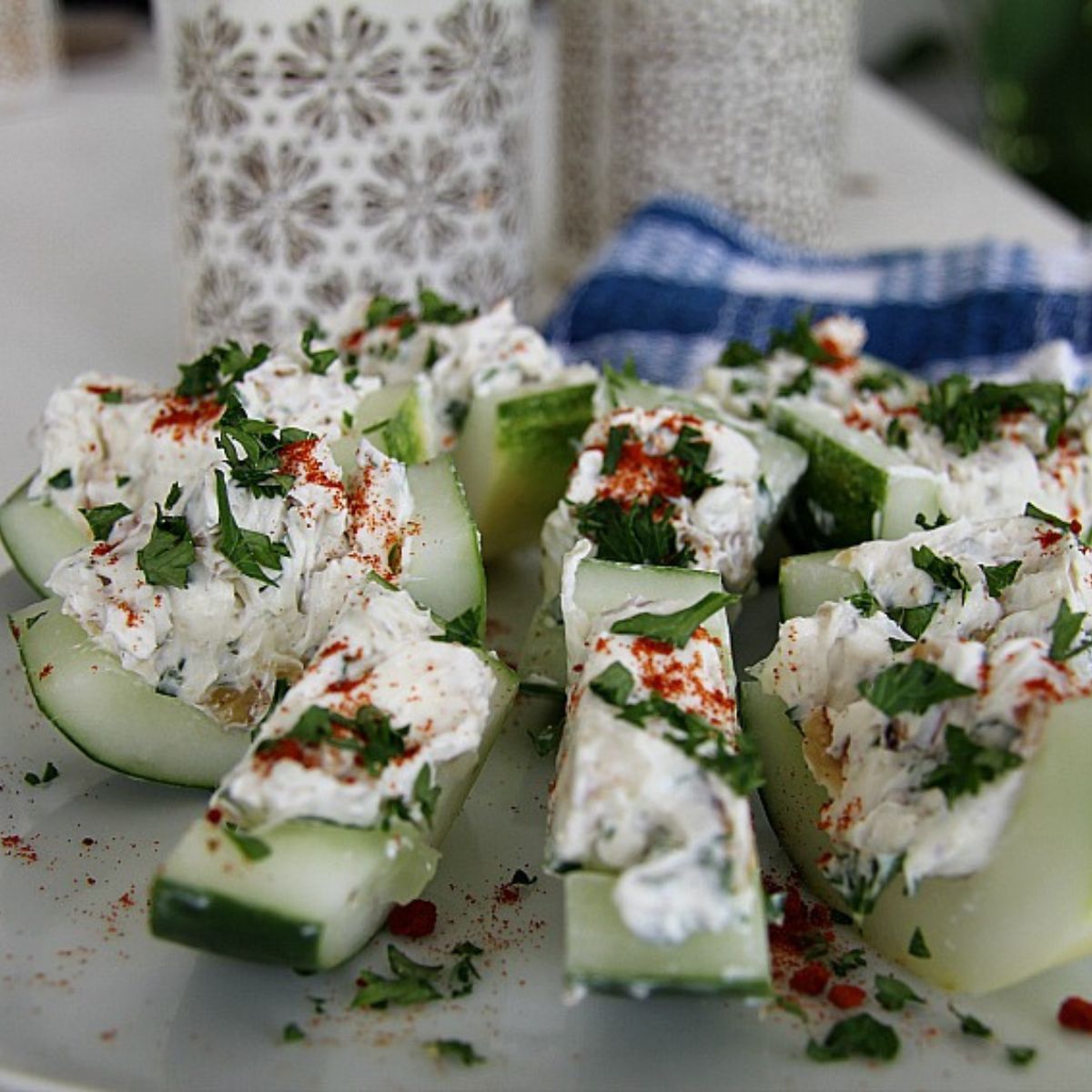 Cucumber bites topped with feta cheese and herbs on a plate.