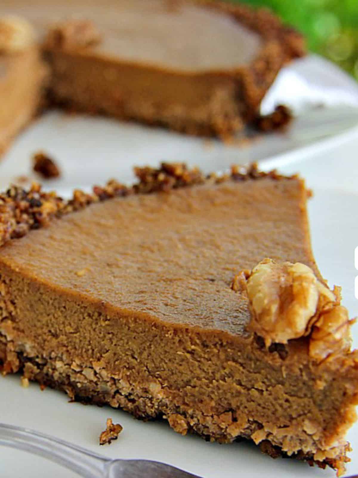 A slice of walnut pumpkin pie with a nutty crust, beautifully topped with a single walnut.