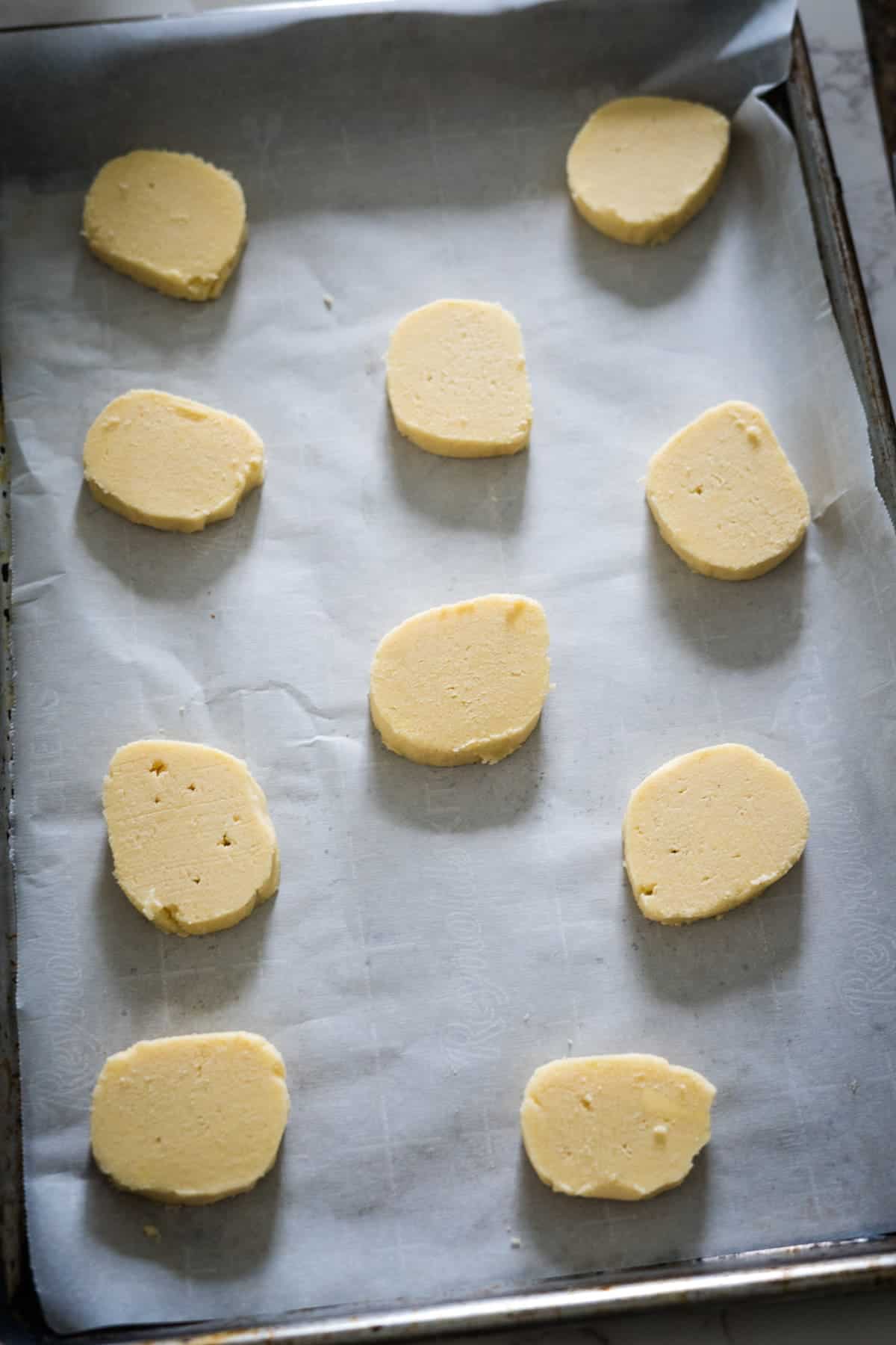 Keto cream cheese cookie dough portions arranged on a parchment-lined baking sheet, ready for baking.