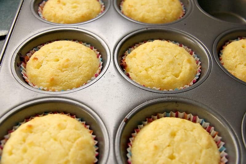 Freshly baked lemon coconut muffins in a muffin tin.