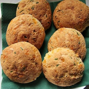 A basket of freshly baked low carb herb rolls with a golden crust, served in a green napkin.