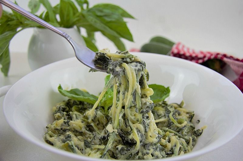 A bowl of zucchini noodles with spinach and cheese.