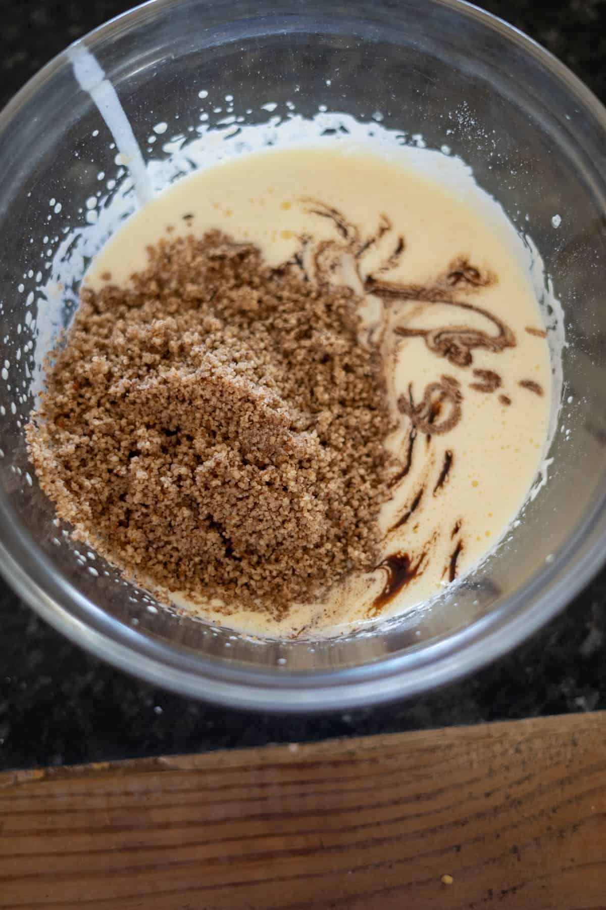 A glass bowl with cake batter, brown sugar, and vanilla extract being mixed together for a delightful pecan torte.