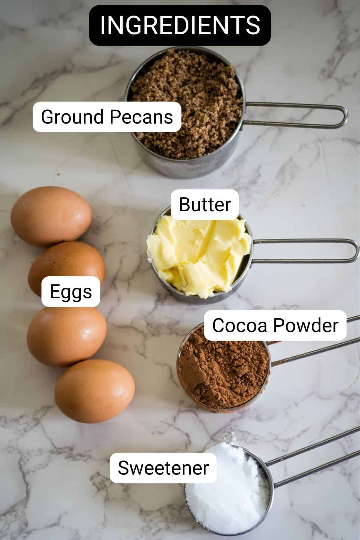 On a marble surface, the essentials for a delicious pecan torte await: four eggs, ground pecans, butter, cocoa powder, and sweetener carefully measured in cups.