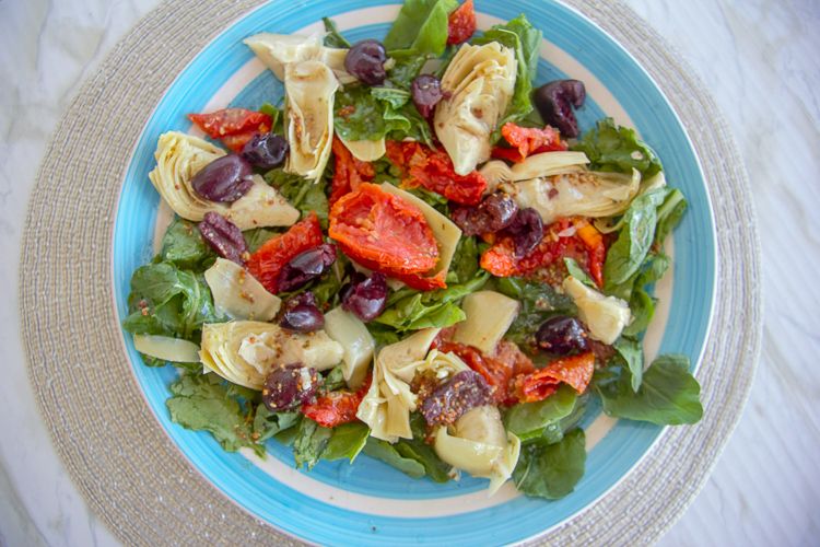 a salad made with arugula leaves, artichokes, olives and sun-dried tomatoes