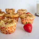 Keto strawberry crumb muffins on a plate next to a glass of milk.