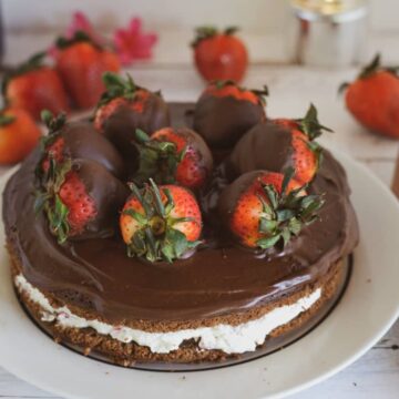 A chocolate-covered strawberries cake with a decadent layer of whipped cream, beautifully displayed on a white plate.