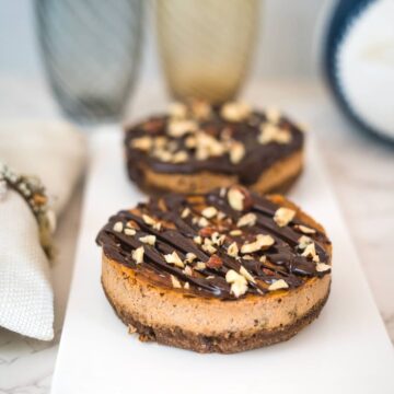 chocolate cheesecakes with a topping of chocolate and nuts on a plate