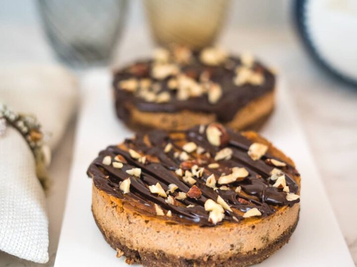 chocolate cheesecakes with a topping of chocolate and nuts on a plate