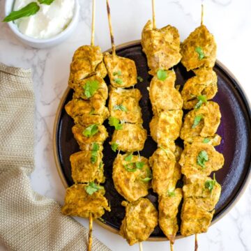 spiced chicken on skewers on a plate