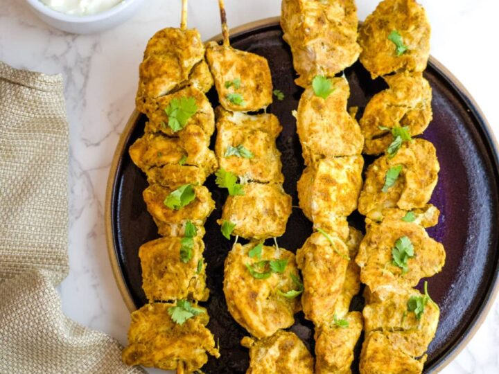 spiced chicken on skewers on a plate