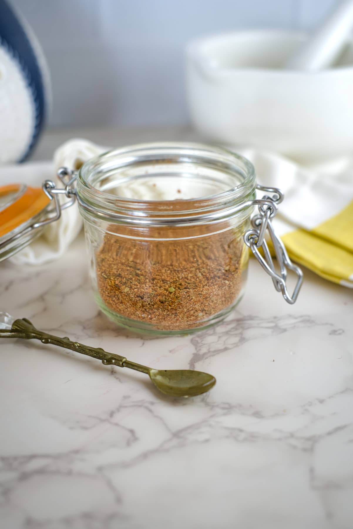 cajun spice mix in a glass jar with small spoon