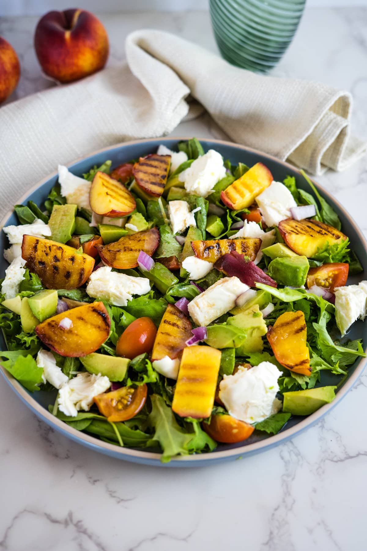 grilled peaches, mozzarella and avocado salad on a plate.
