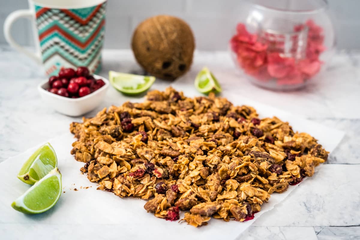 Cranberry granola on a white plate next to a cup of coffee.