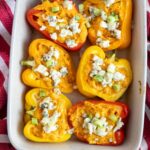 Stuffed peppers in a white dish with blue cheese.