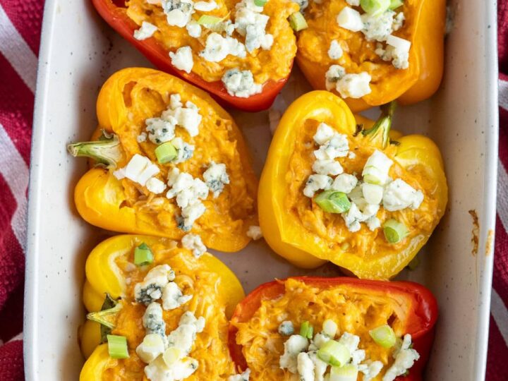 Stuffed peppers in a white dish with blue cheese.