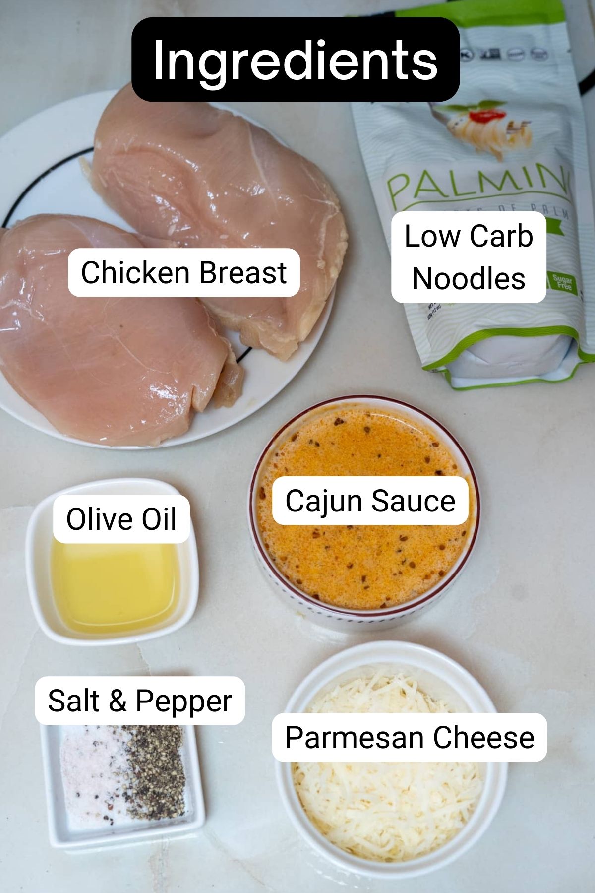 The ingredients for chicken parmigiana are shown on a white table.