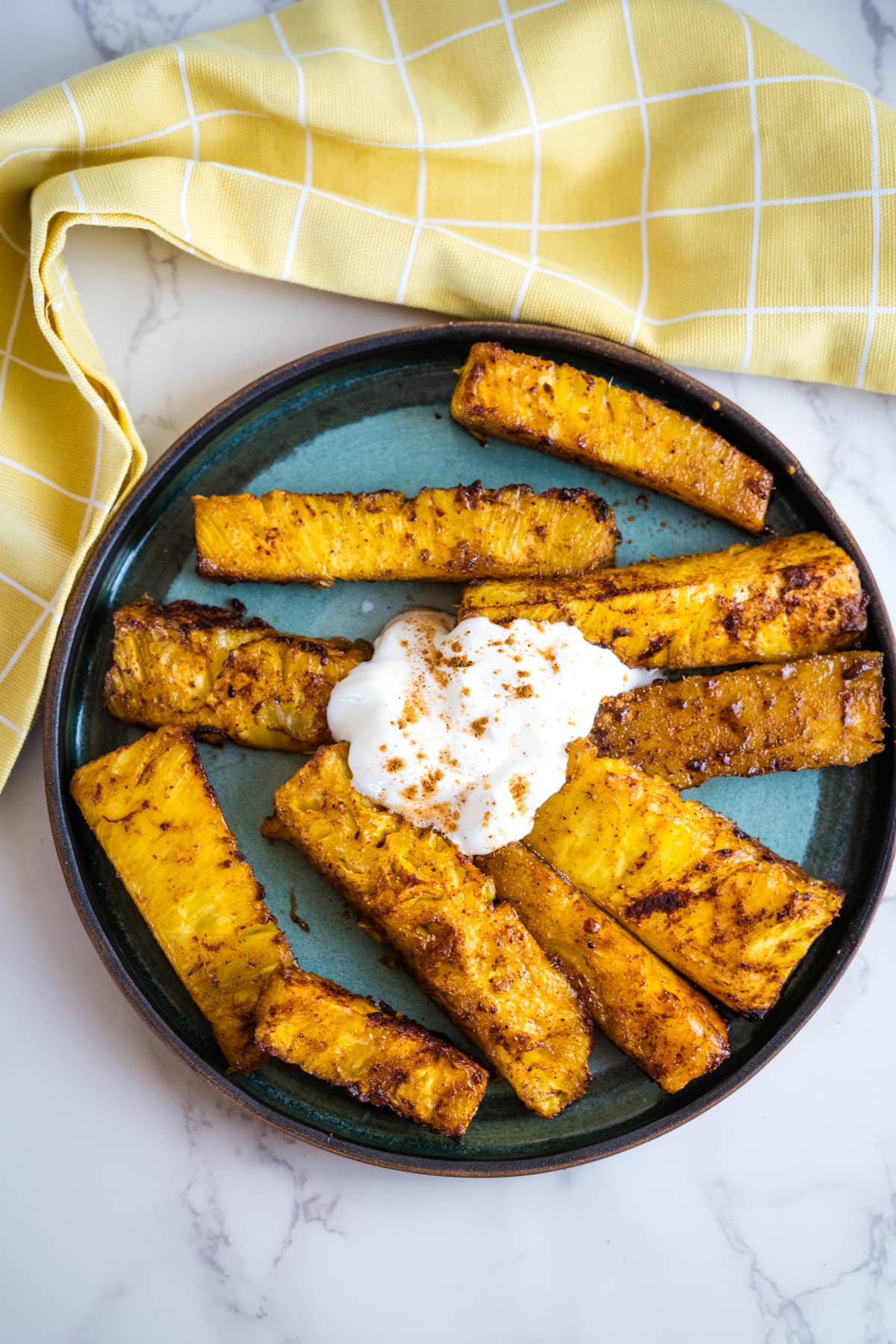 Air-fried pineapple wedges with cream on a plate.