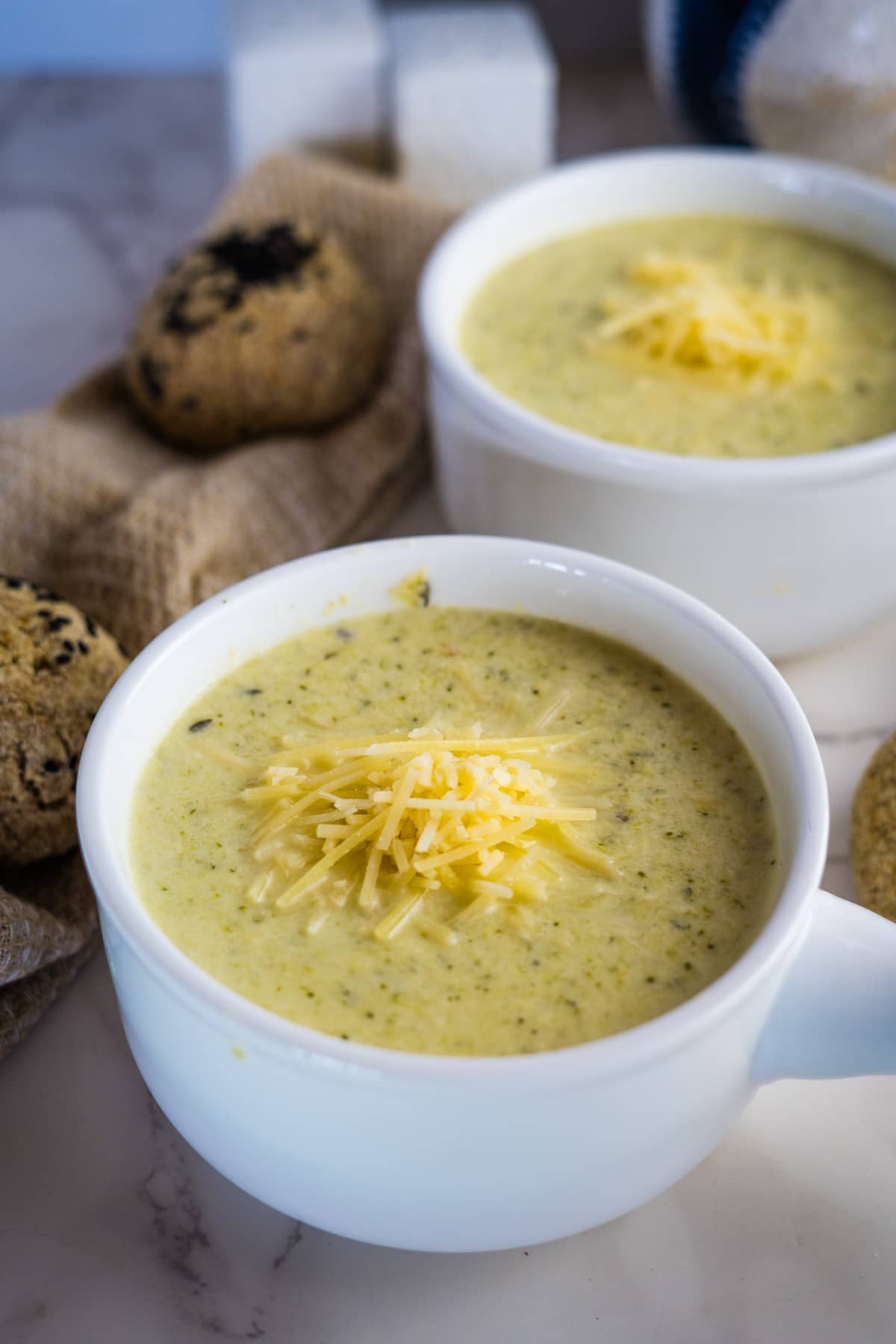 Two bowls of soup with cheese and bread.