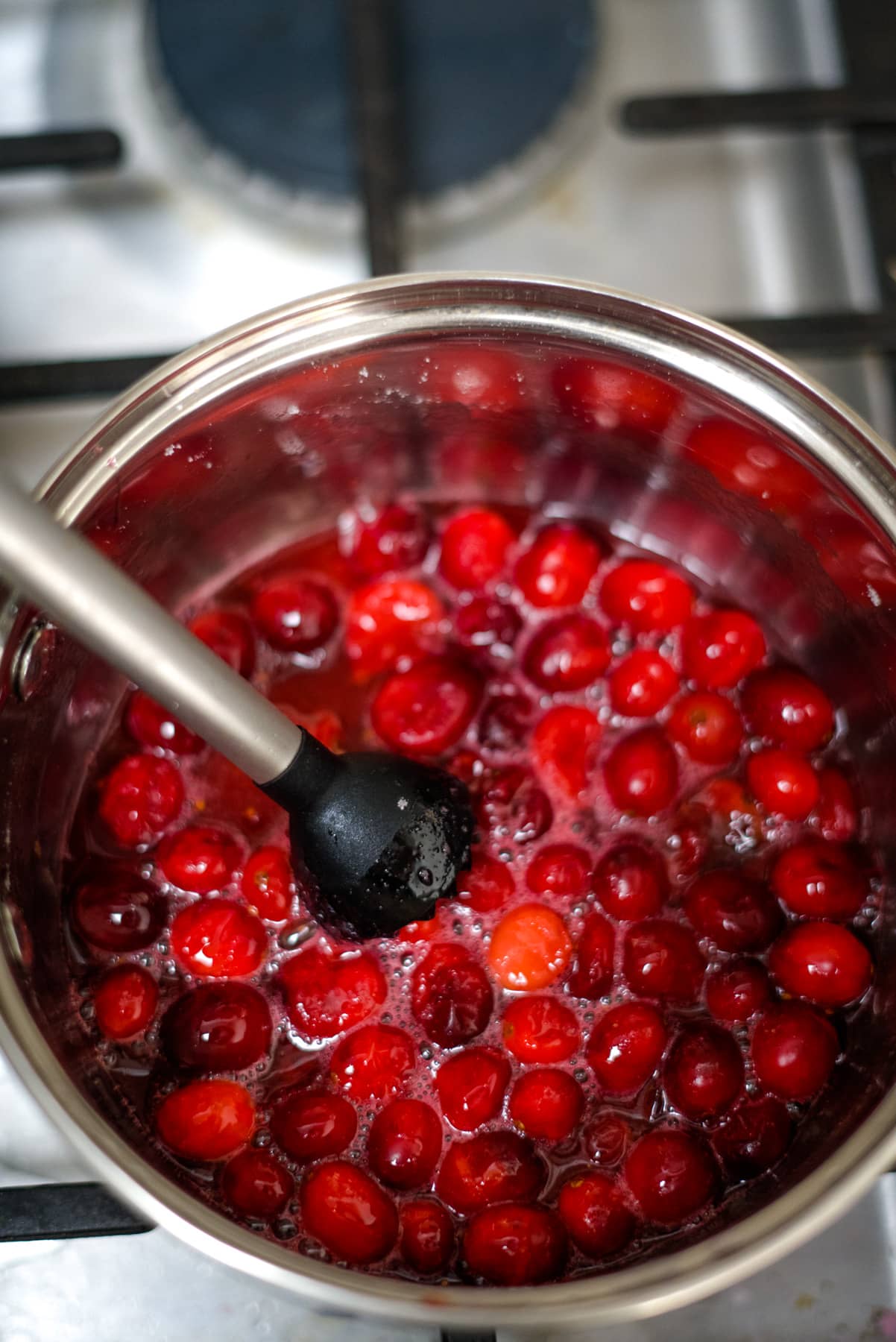 Cranberries simmering in a pot on a stove for cranberry mimosa.