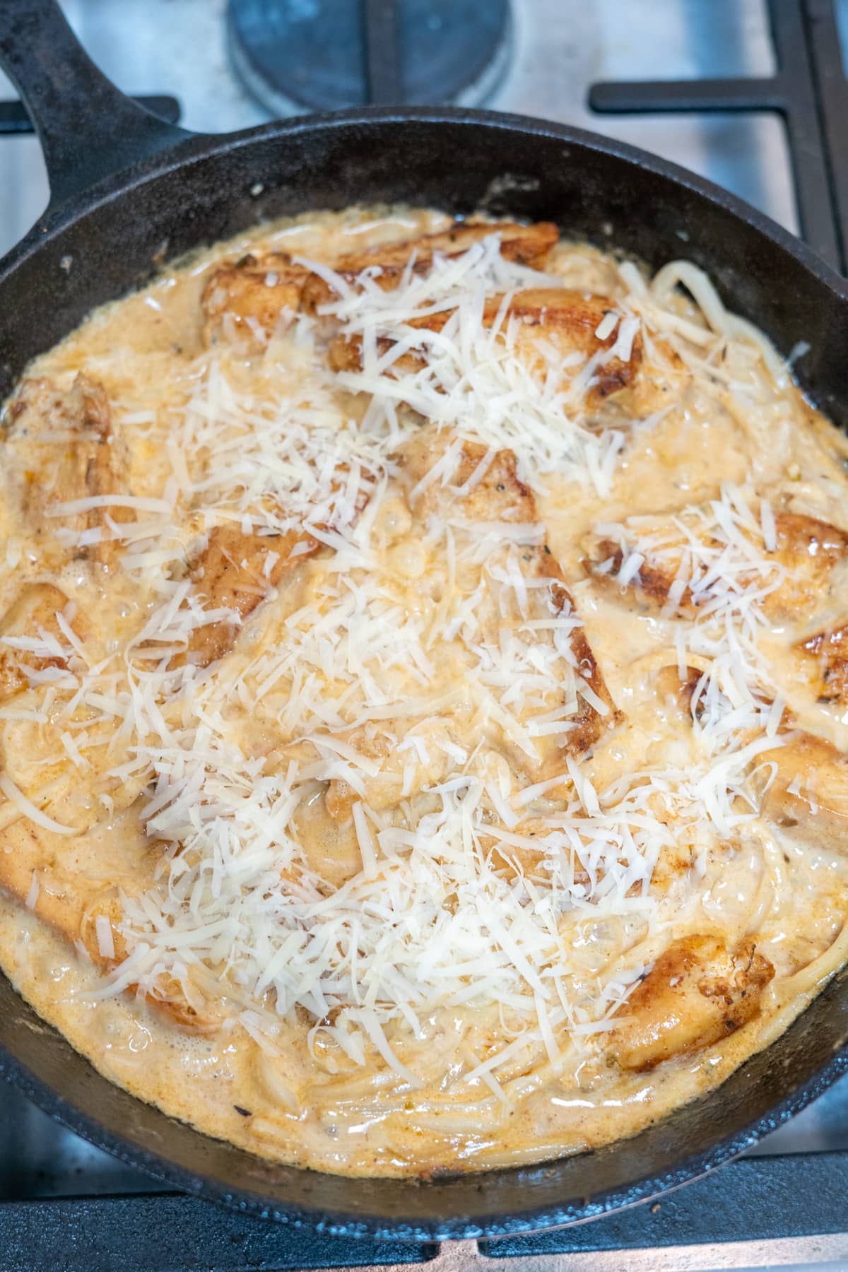 A skillet filled with cajun chicken and cheese on a stove top.