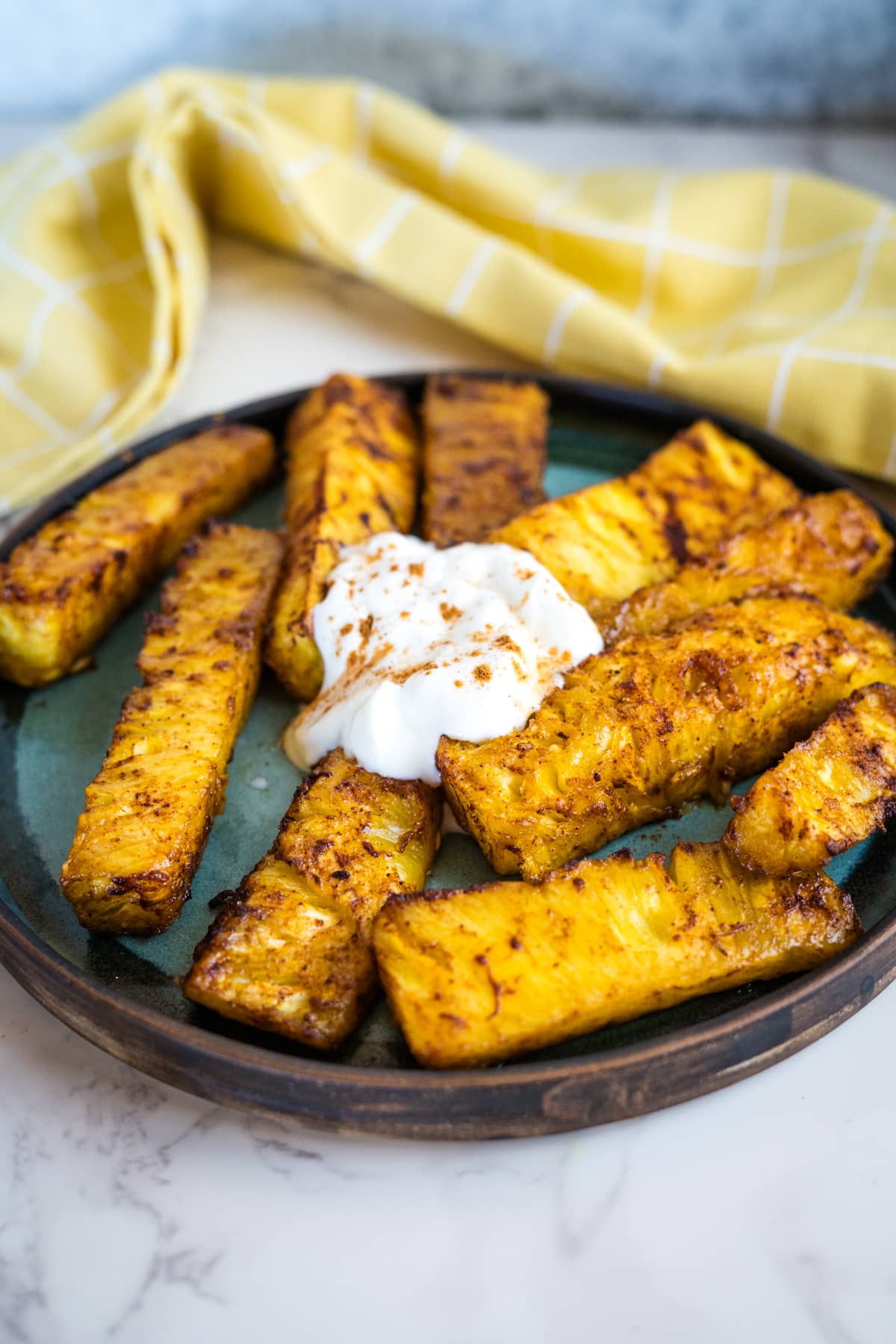 Grilled pineapple wedges with sour cream on a plate.