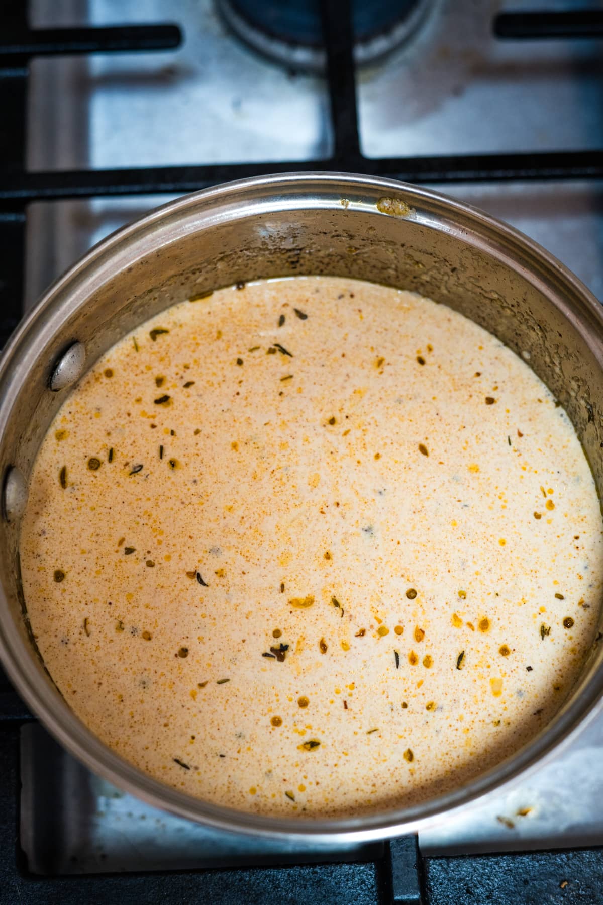 A pan on a stove with cajun alfredo sauce.