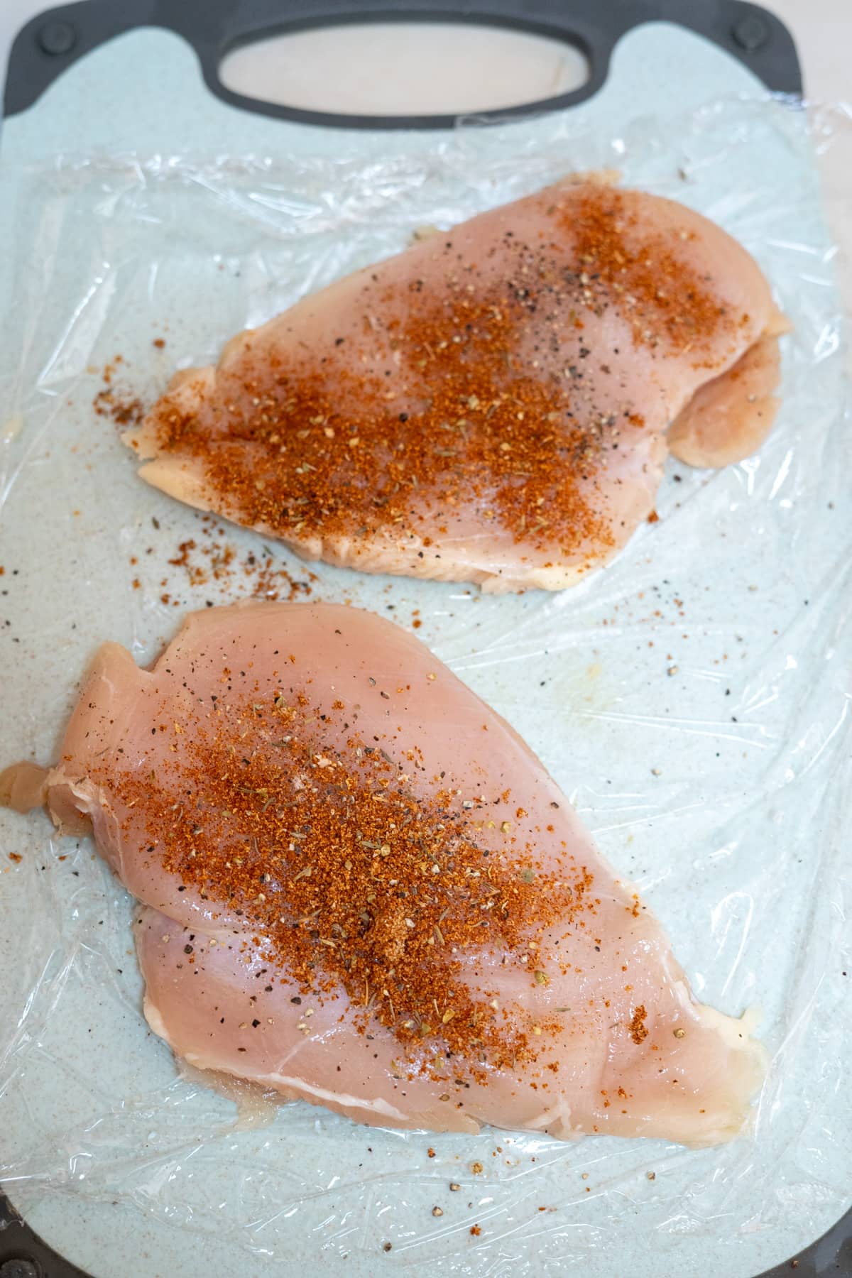 Two Cajun seasoned chicken breasts on a baking sheet.