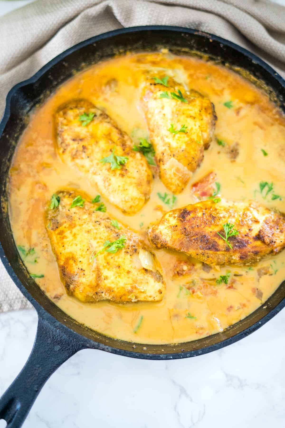 A Brazilian coconut chicken dish cooked in a cast iron skillet, smothered in a creamy sauce.
