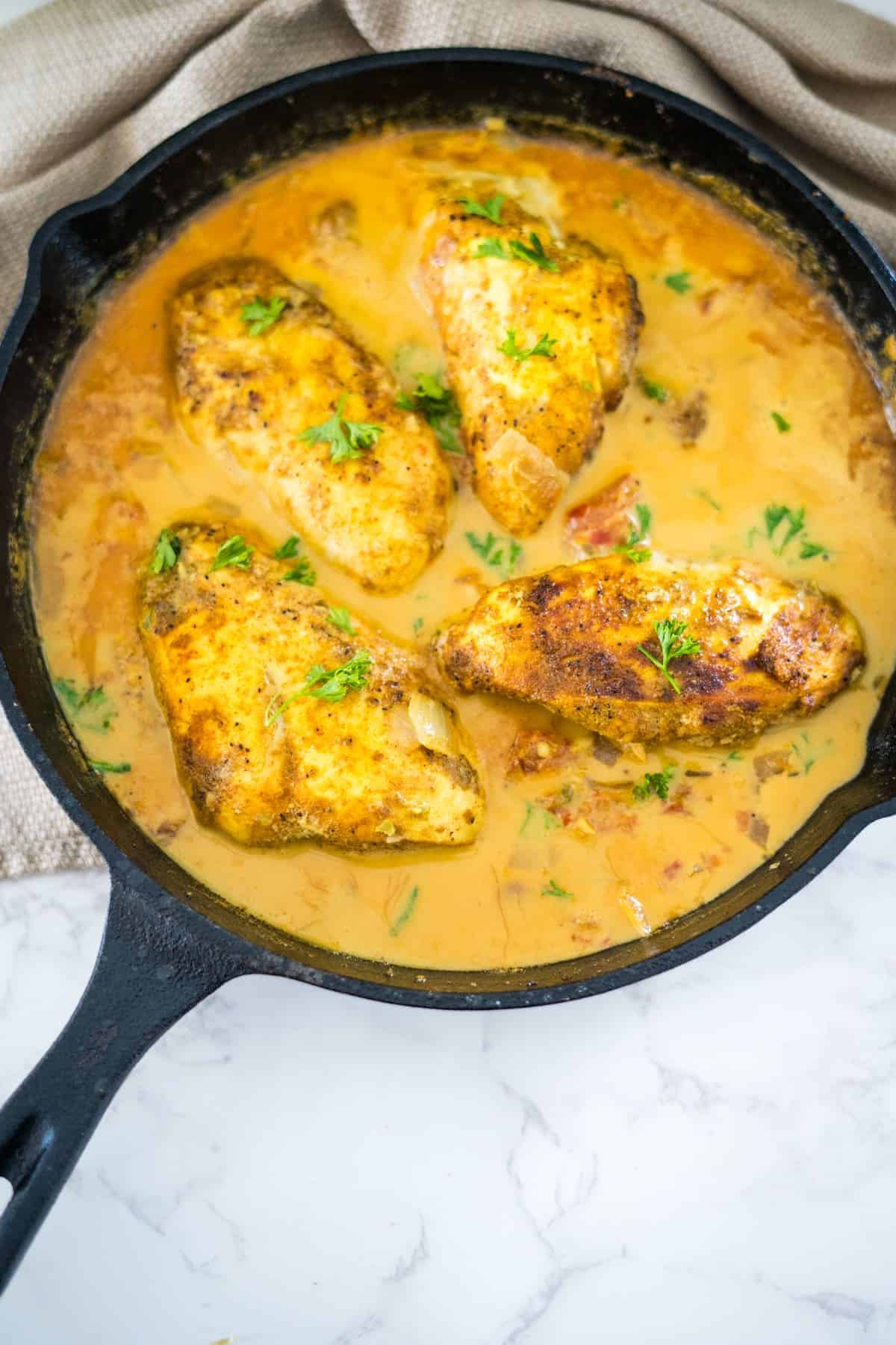 A Brazilian coconut chicken dish cooked in a cast iron skillet with a creamy sauce.