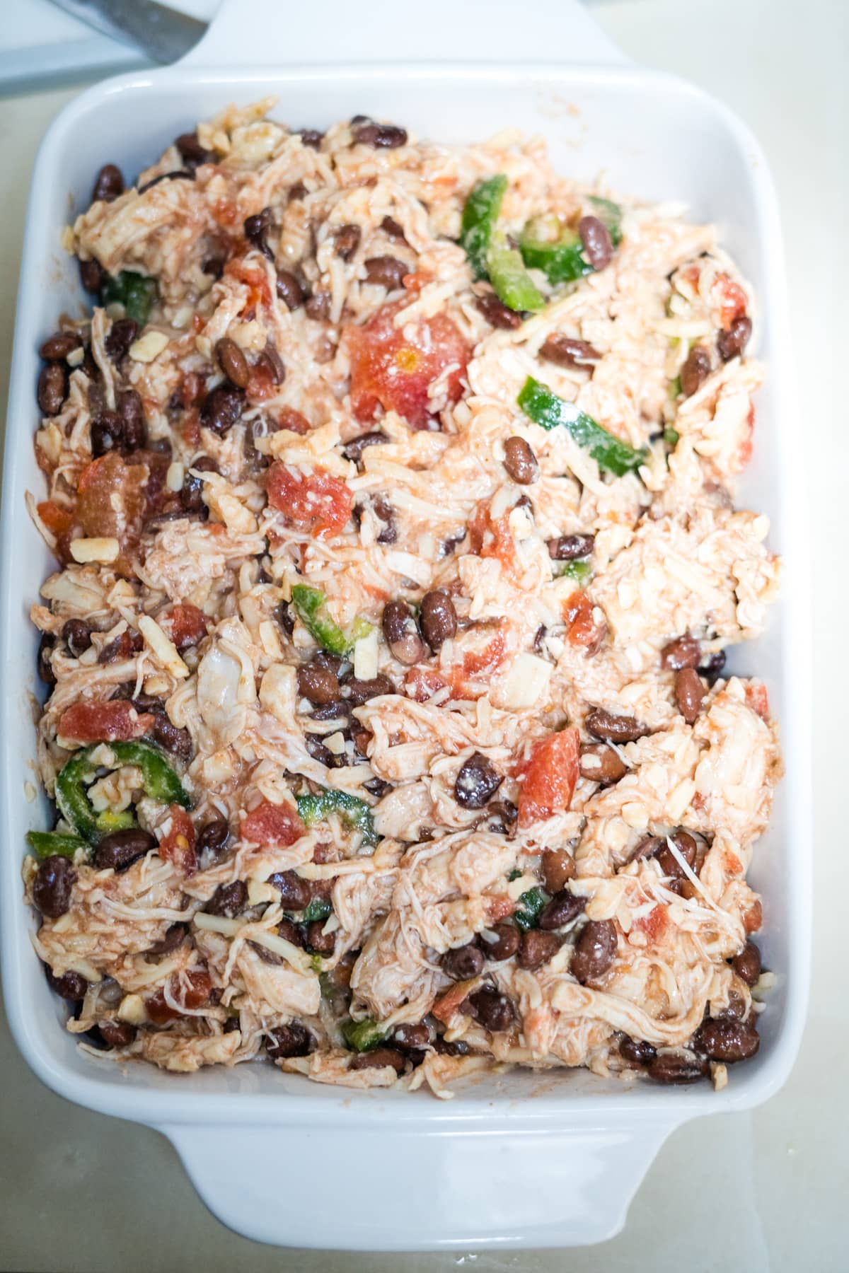 A casserole dish with chicken, black beans and tomatoes.